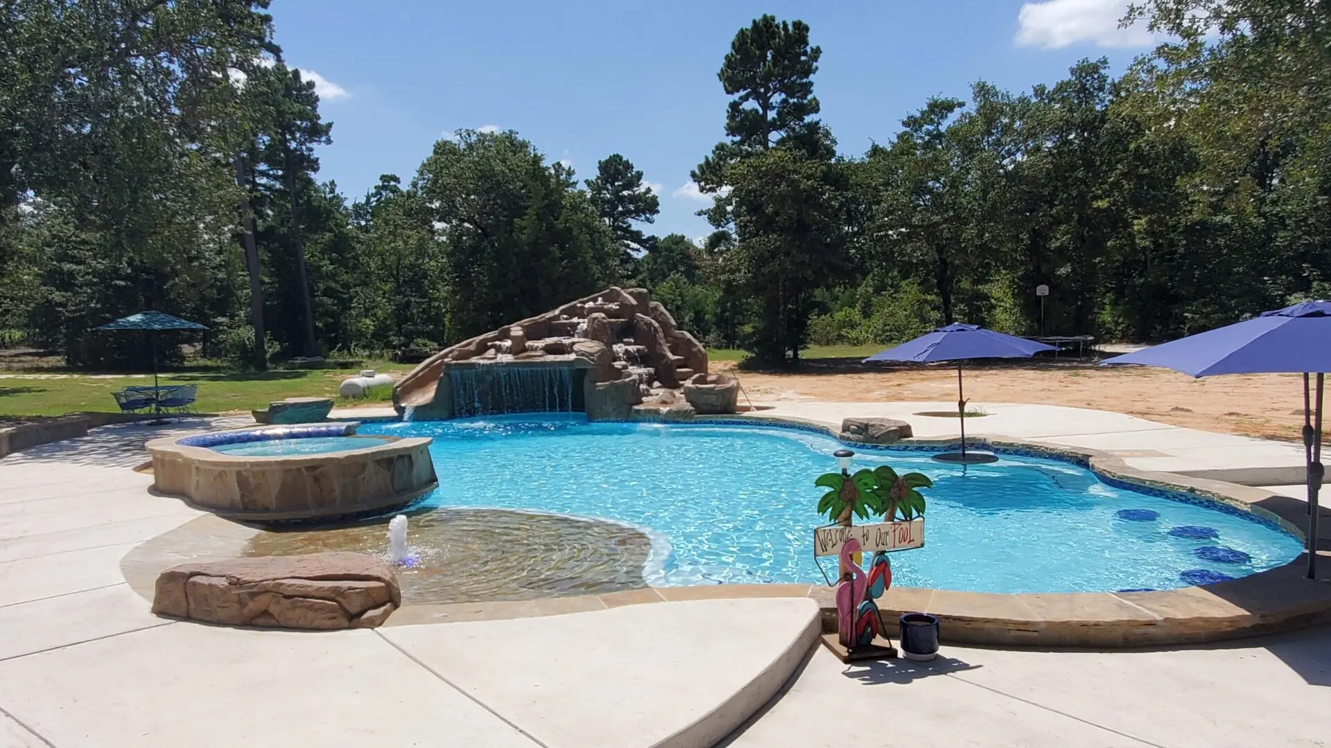 Family custom pool with a rock waterfall, slide, spa and beach entry