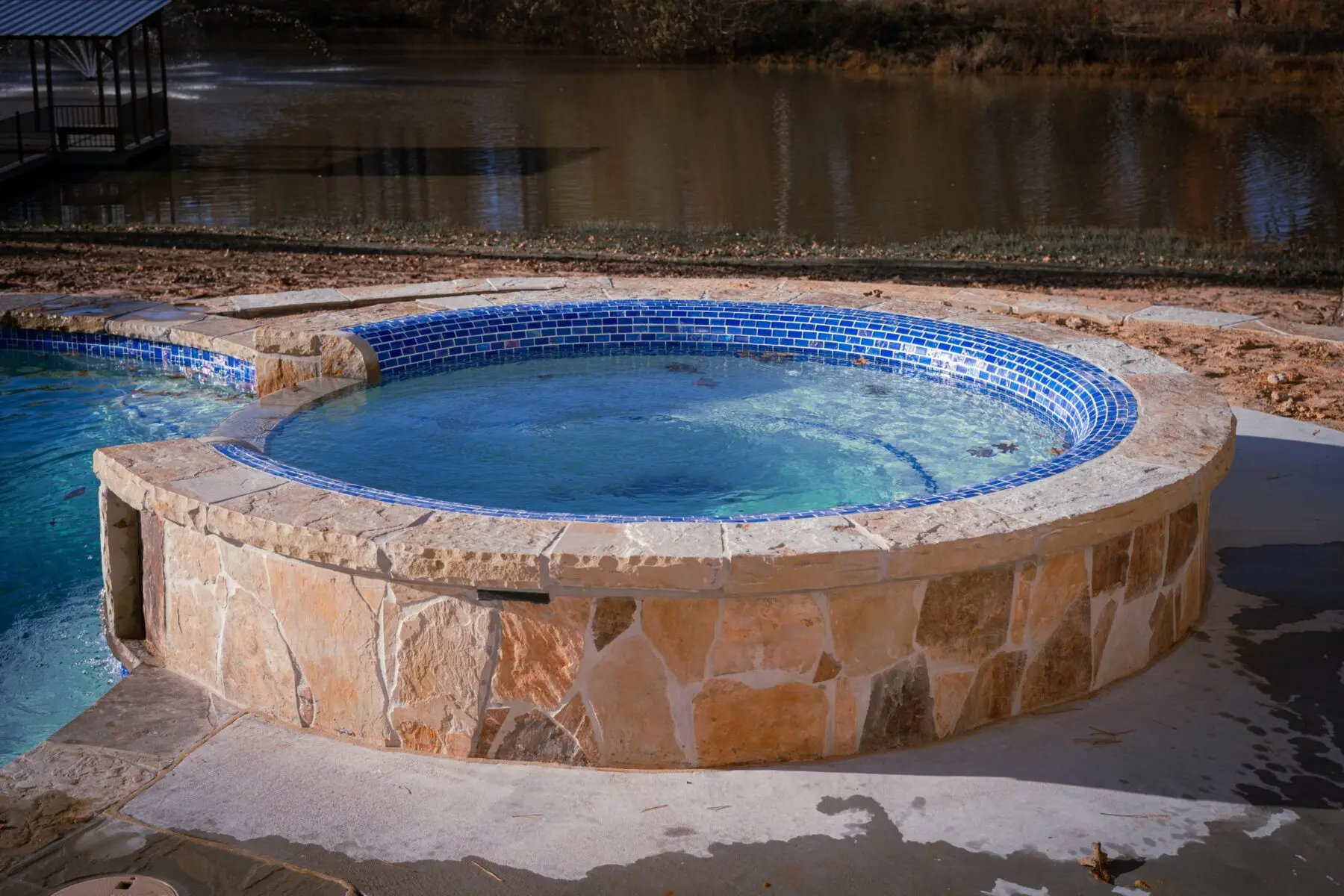 Round custom spa with a flagstone surround and blue glass tile